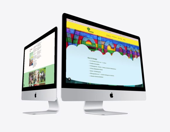 Zwei iMac-Computer zeigen eine bunte Website mit "Willkommen"-Banner.